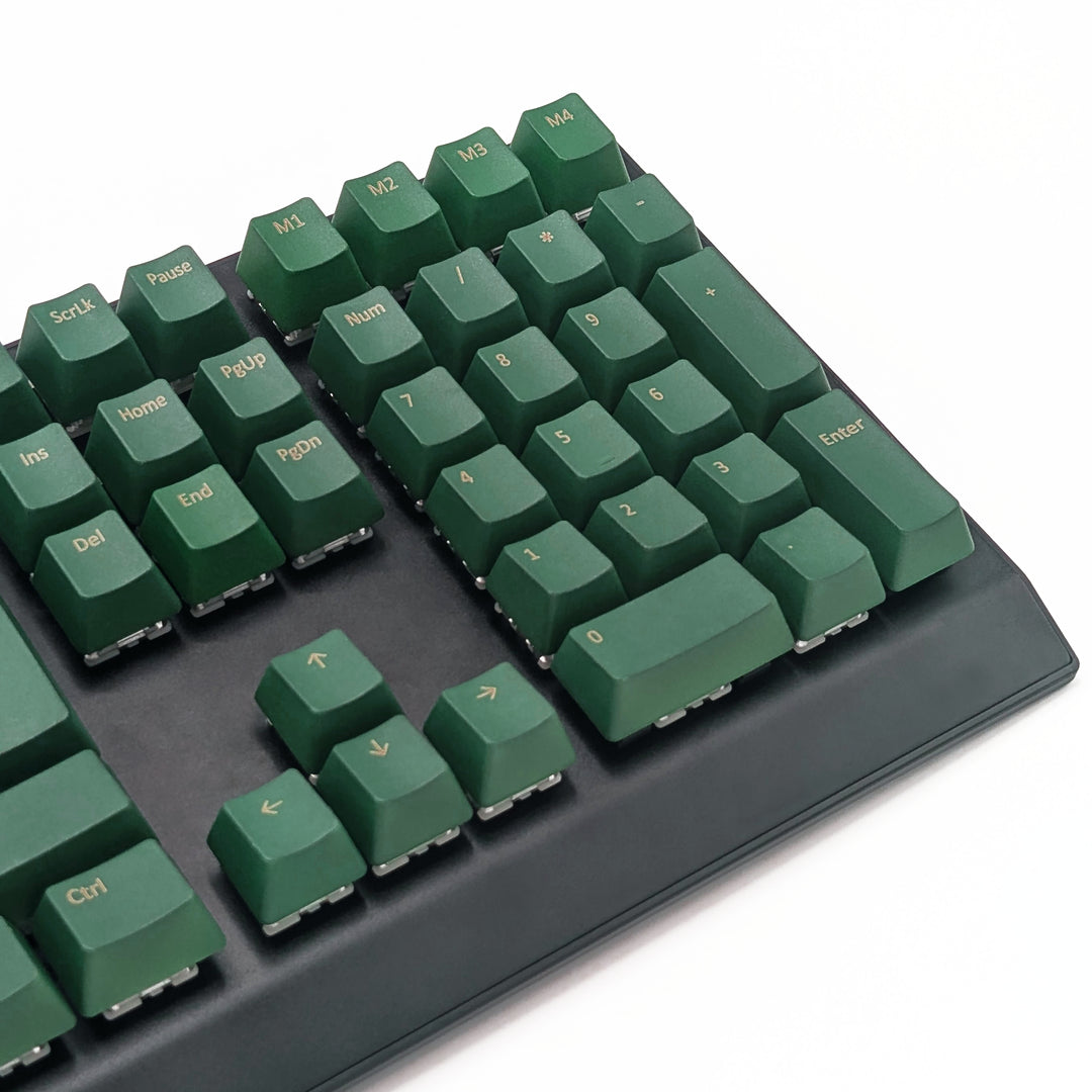 Mechanical keyboard fitted with customisable green QWERTY PBT keycaps, non-backlit OEM profile with gold legends and ISO-compatible layout.