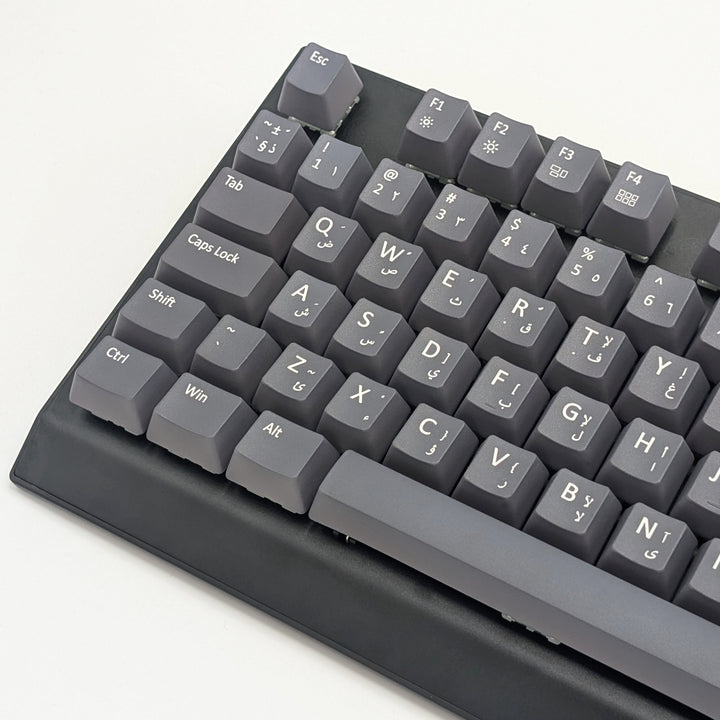 Close-up of grey QWERTY PBT keycaps with white legends, non-backlit OEM profile keys with a matte finish on a mechanical keyboard.