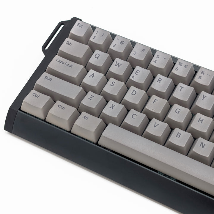 Close-up of light grey QWERTY PBT keycaps with grey legends, non-backlit OEM profile keys with a matte finish on a mechanical keyboard.
