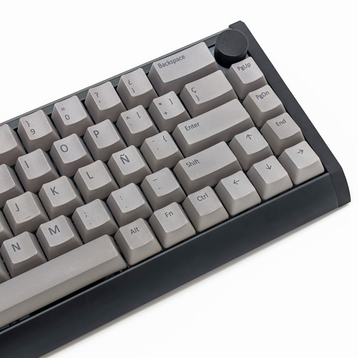 Close-up of light grey QWERTY PBT keycaps with grey legends, non-backlit OEM profile keys with a matte finish on a mechanical keyboard.