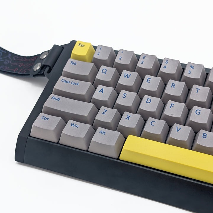 Close-up of light grey QWERTY PBT keycaps with blue legends, non-backlit OEM profile keys with a matte finish on a mechanical keyboard.