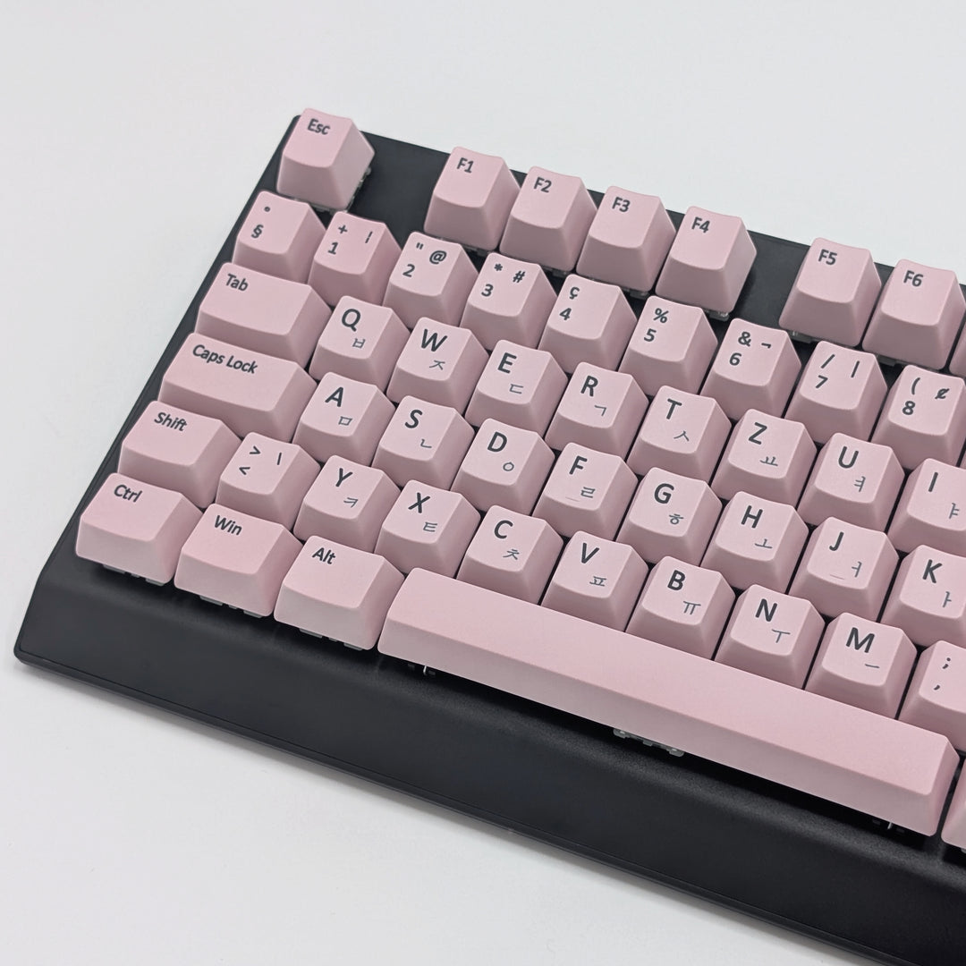 Close-up of Light Pink QWERTZ PBT keycaps with black legends, non-backlit OEM profile keys with a matte finish on a mechanical keyboard.
