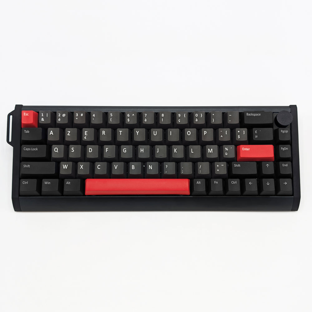 A compact black mechanical keyboard with red accent keys and a red backplate on the spacebar, photographed from directly above on a clean white background.