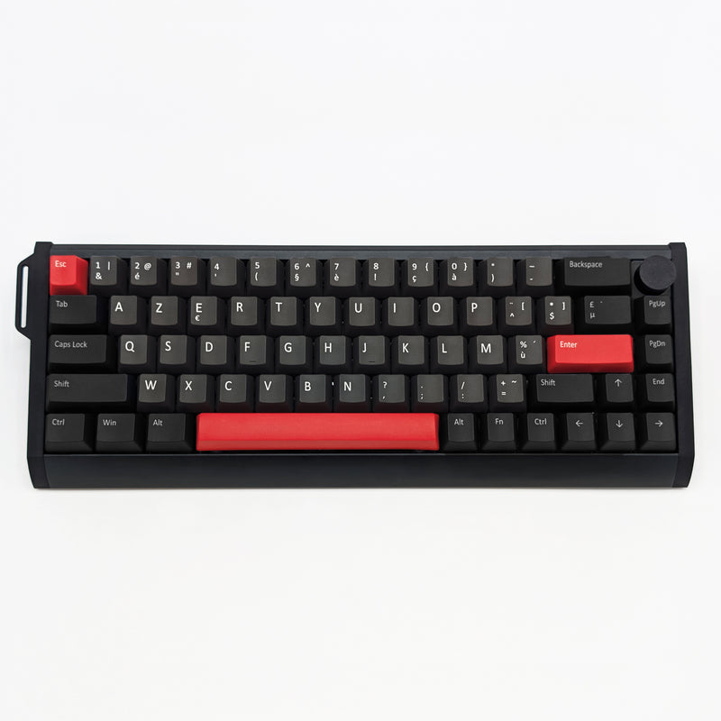 A compact black mechanical keyboard with red accent keys and a red backplate on the spacebar, photographed from directly above on a clean white background.