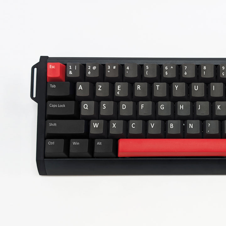 A close-up of a black mechanical keyboard with a distinctive red escape key and a red spacebar, shown on a clean white background.