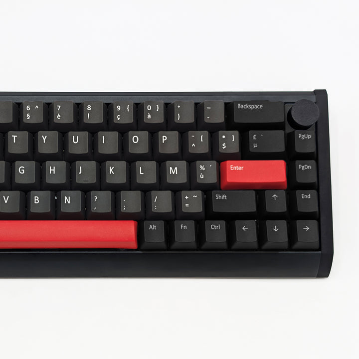 A close-up of a black mechanical keyboard showing the top row of keys, including a prominent red Enter key and a red horizontal accent bar, with a black knob on the right side, set against a plain white background.