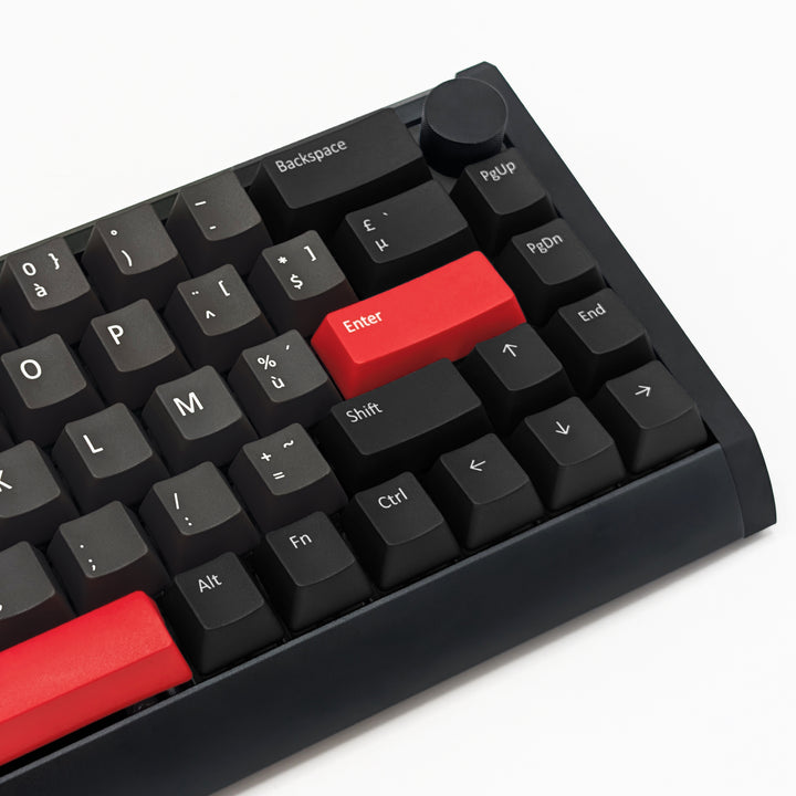 Close-up of a black mechanical keyboard with two prominent red keycaps, including the Enter key and the backspace key, on a clean white background.