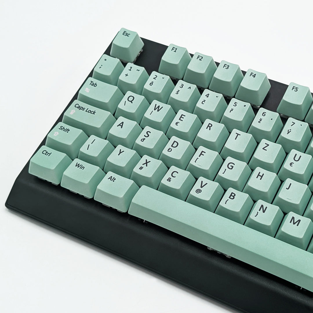 Close-up of Mint QWERTZ PBT keycaps with black legends, non-backlit ISO-compatible OEM profile keys with matte finish on a mechanical keyboard.