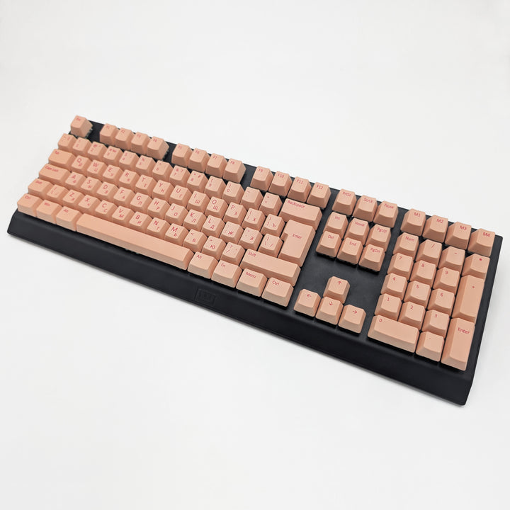 Peach ISO-compatible OEM profile QWERTY PBT keycaps with matte finish installed on a mechanical keyboard, showing non-backlit keys with dye-sublimated cherry red legends.