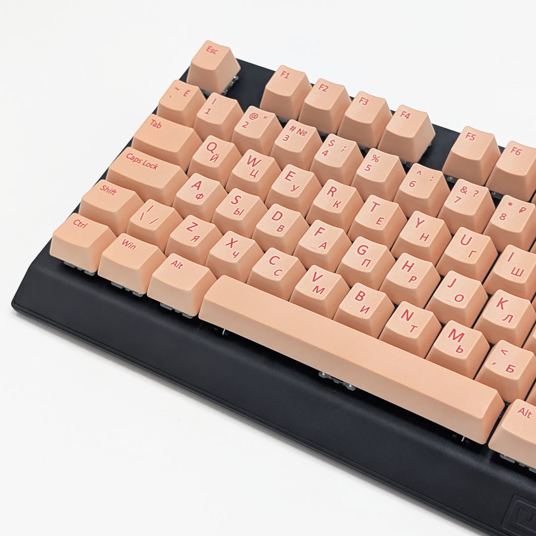 Close-up of Peach QWERTY PBT keycaps with cherry red legends, non-backlit ISO-compatible OEM profile keys with matte finish on a mechanical keyboard.