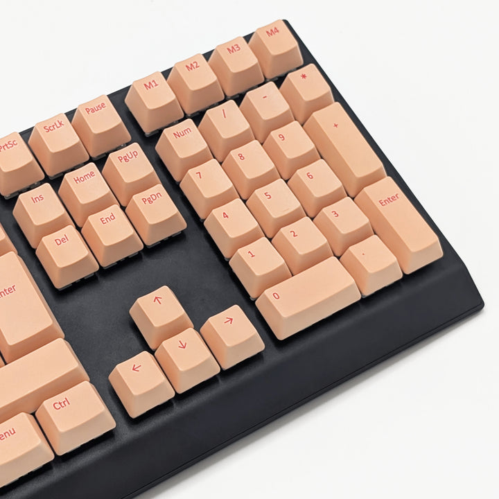 Mechanical keyboard fitted with customisable Peach QWERTY PBT keycaps, non-backlit ISO-compatible OEM profile with cherry red legends and matte finish.