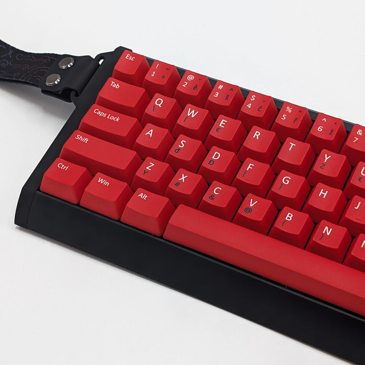 Close-up of red PBT keycaps with white and black legends, non-backlit ANSI QWERTY OEM profile keys with matte finish on a mechanical keyboard.