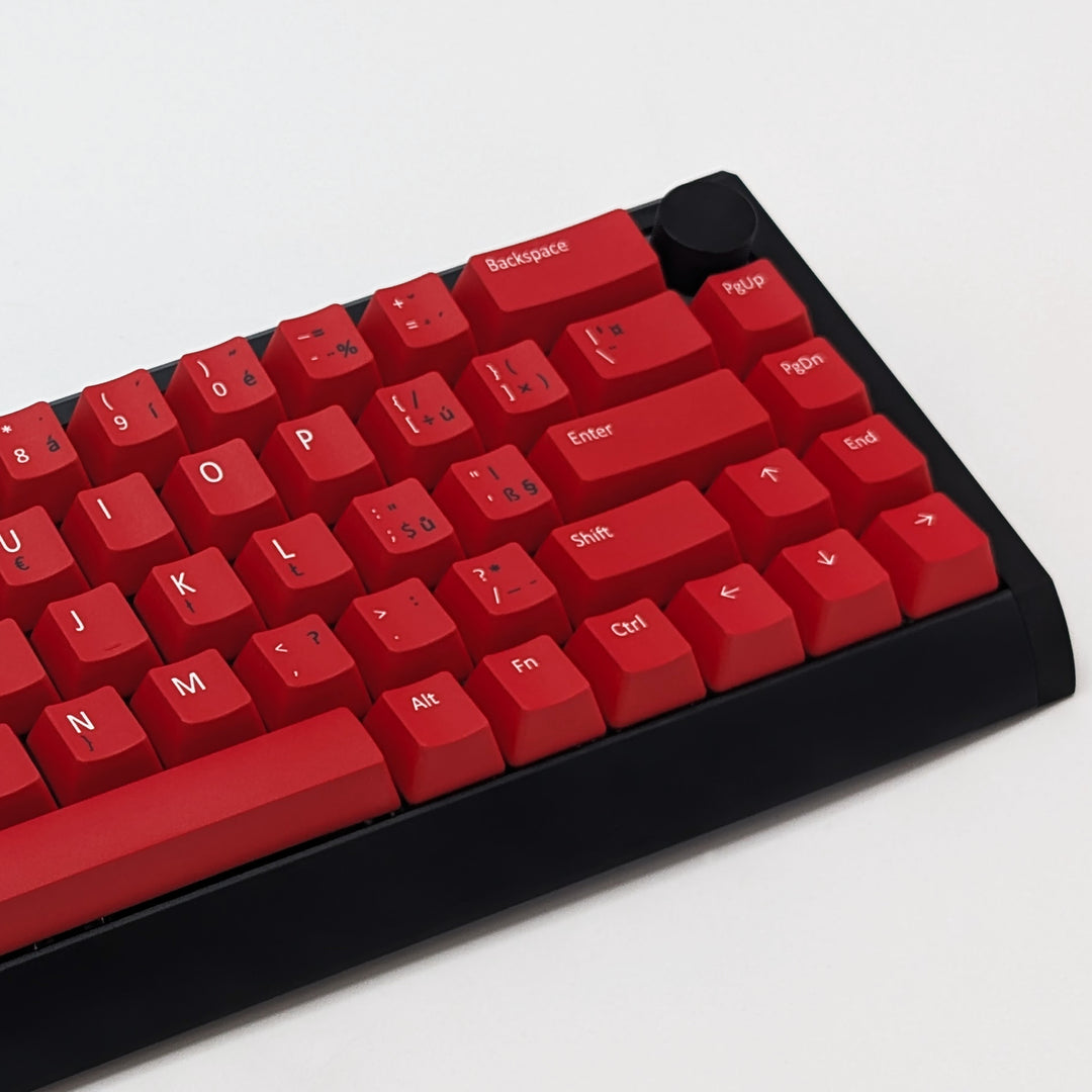 Mechanical keyboard fitted with customisable red PBT keycaps, non-backlit ANSI QWERTY OEM profile with white and black legends and matte finish.