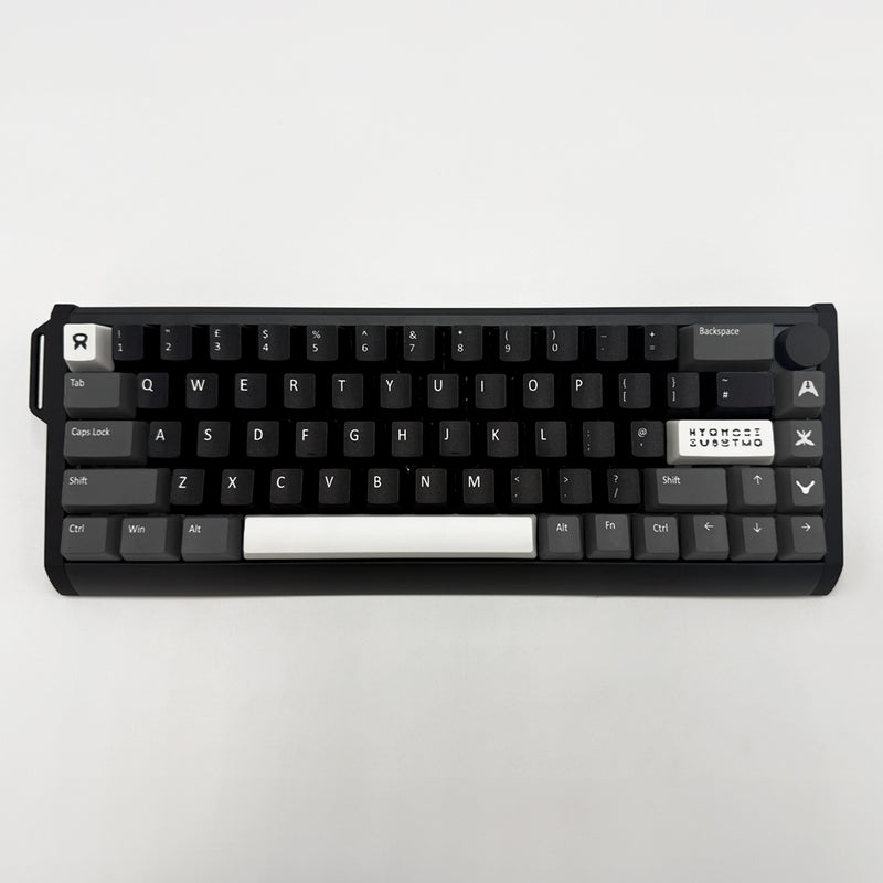 A compact mechanical keyboard with black keycaps and a white spacebar, photographed from directly above on a light gray background.