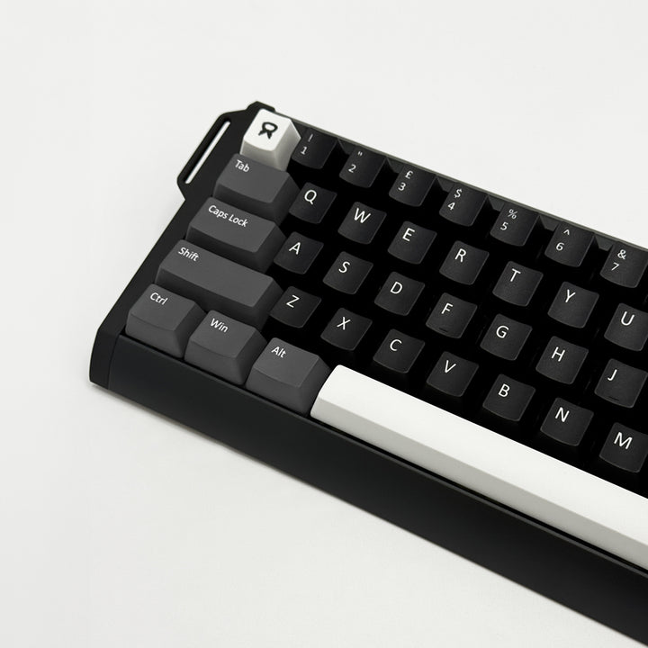 A close-up of a mechanical keyboard with a black case, black keycaps, and a prominent white WASD row and white Enter keycap, photographed on a clean white background.