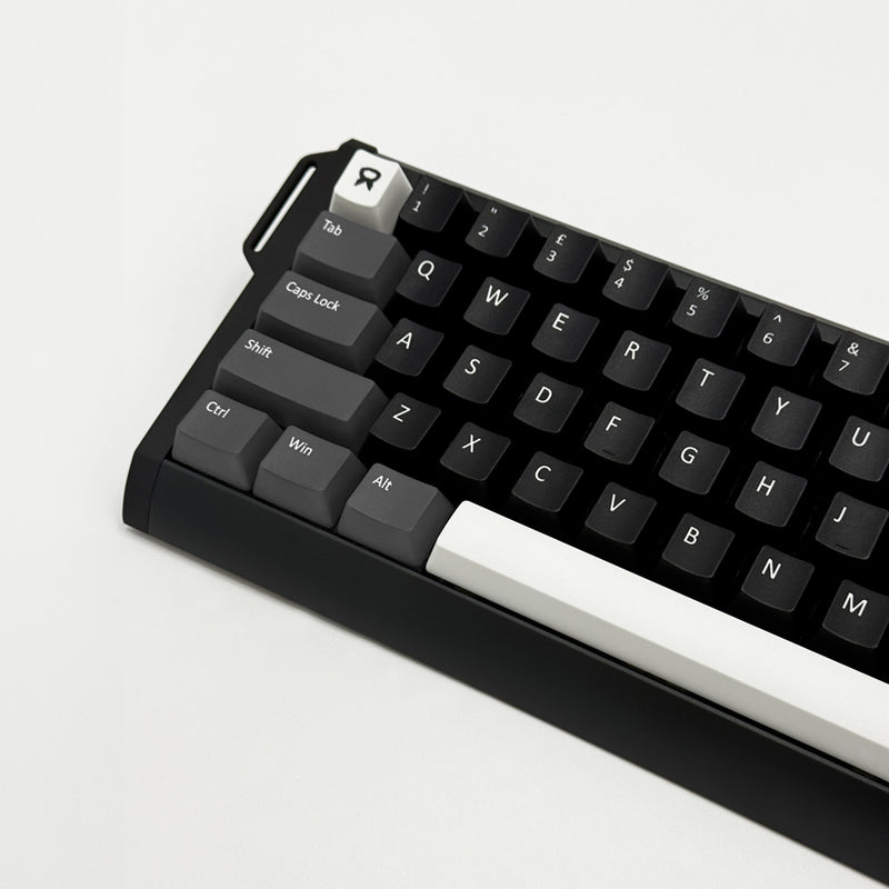 A close-up of a mechanical keyboard with a black case, black keycaps, and a prominent white WASD row and white Enter keycap, photographed on a clean white background.