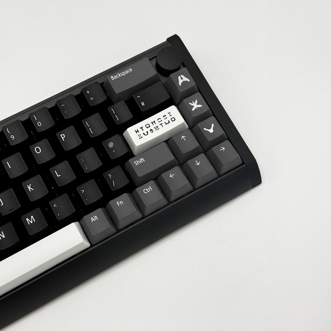 A close-up of a black mechanical keyboard with custom white keycaps, including a central keycap printed with &